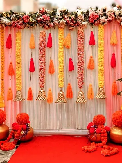 This vibrant backdrop is perfect for home functions like a Haldi ceremony or a small puja. I combined curtains of bright marigolds, colorful tassels, and traditional brass bells to create a cheerful and auspicious setting for photos and rituals.