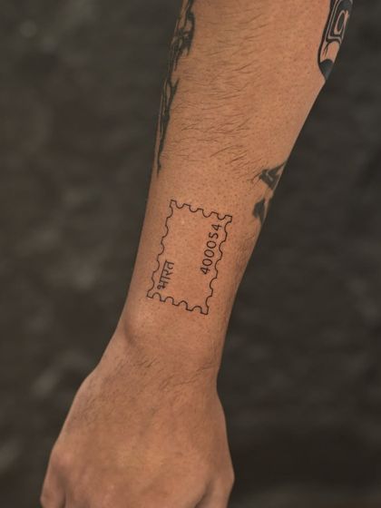 A minimalist stamp tattoo with a Mumbai pin code, a unique and personal "stamp of our origin story" for a client.