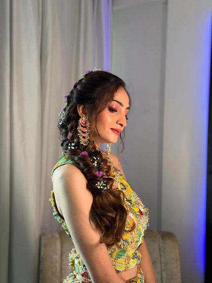 A side profile of the romantic messy braid, showing the soft tendrils framing the face and the delicate floral details.