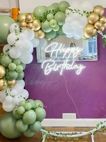 An elegant, rustic-themed balloon ring decoration for a birthday. This design uses sage green, white, and gold balloons with faux ivy vines wrapped around a white ring frame for a natural look.