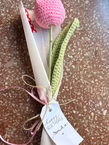 A close-up of a single pink crochet tulip, showing the handwritten "Happy Birthday" tag. Every gift gets a personal touch from me.