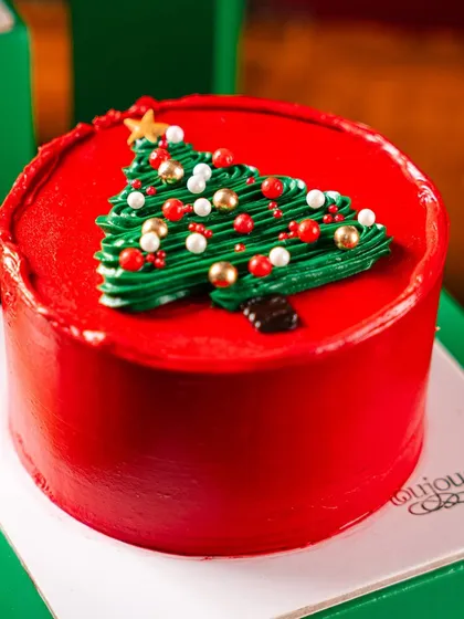 Our Christmas Tree Mini Cake, a vibrant red cake topped with a piped green Christmas tree. It's a cheerful and delicious little cake that captures the spirit of the season.