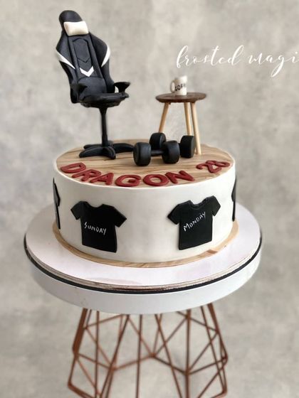 A cake celebrating a few favourite things: gaming, coffee, and fitness. The t-shirts around the side add another layer of personalization.