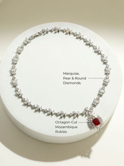 The Ruby Dynasty necklace laid out, showing the intricate arrangement of marquise, pear, and round diamonds leading to the stunning octagon-cut ruby pendant.