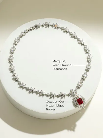 The Ruby Dynasty necklace laid out, showing the intricate arrangement of marquise, pear, and round diamonds leading to the stunning octagon-cut ruby pendant.