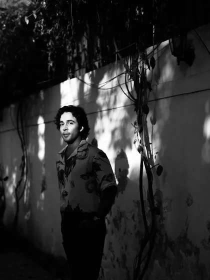 Zahan Kapoor in black and white, with dappled light creating patterns on the wall behind him. I love using natural shadows to add texture to a scene.