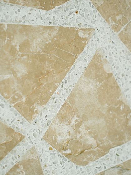 A close-up of our Venetian terrazzo tiles with a mosaic-like pattern, using beige stone chips set in a white concrete base.