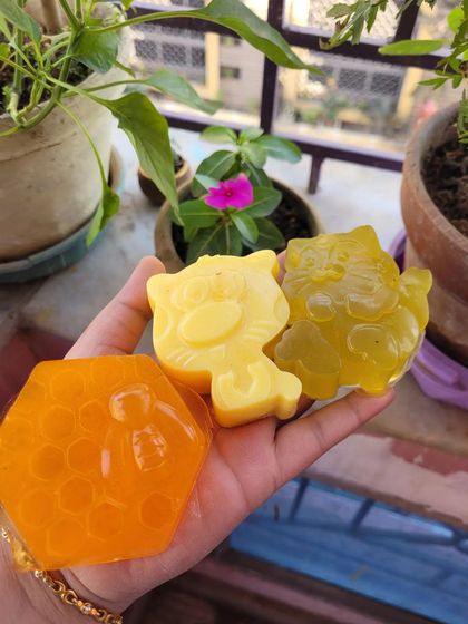 Holding a few of my handmade soaps, including honey and lemon based ones in fun shapes.