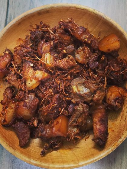 A top-down view of the Pork with Dry Bamboo Shoot served in a rustic wooden bowl. The contrast between the dark, rich pork and the lighter bamboo shoots is beautiful.