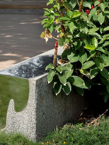 A custom-designed bench made of granite with a polished steel inlay that reflects the sky. This piece is both functional seating and a work of art, placed thoughtfully within the garden to invite pause and interaction.