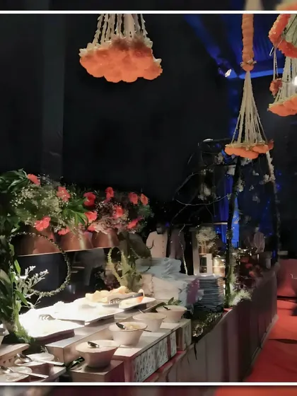 An evening buffet display with hanging floral arrangements. The station is decorated with fresh flowers and greenery, creating a rich and inviting atmosphere for guests.