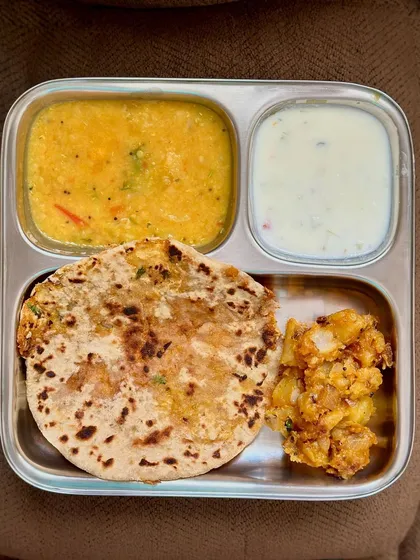 A hearty meal of stuffed paratha, dal, and sautéed potatoes with raita. This is a filling and satisfying lunch option.
