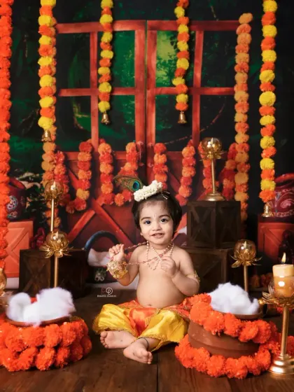 A beautiful and traditional 'Kanha' themed shoot for Janmashtami. The baby is dressed as Lord Krishna, set against a backdrop of marigold garlands and brass lamps.