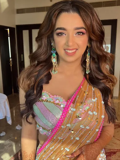 A happy bride ready for her Mehendi party. The soft waves and radiant makeup complete her festive look.
