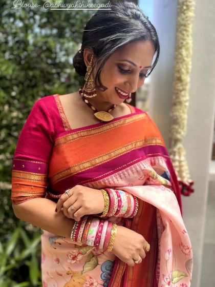 A client in a beautiful floral printed saree with a bright pink and orange border, paired with a custom pink blouse.