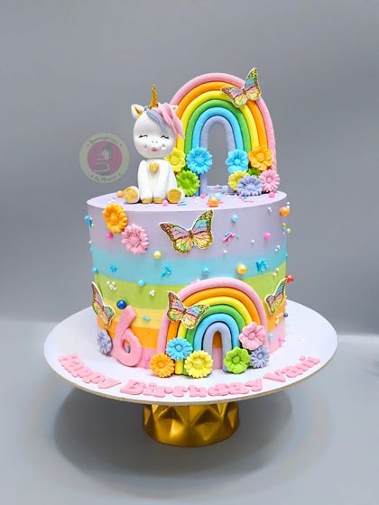A pastel rainbow unicorn cake, decorated with butterflies and flowers for a soft, magical look.