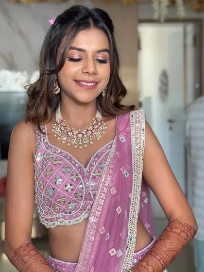 The soft waves and pink tones in her makeup and hair accessory create a harmonious and pretty look, ideal for a daytime wedding event.