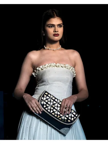 This portrait showcases a model in a strapless white gown, holding an embellished clutch. Our focus here is on capturing the complete look, including accessories, which are crucial for fashion storytelling and brand collaborations.