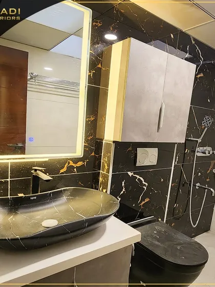 A bold and luxurious bathroom design featuring black marble with dramatic gold veining. The space is equipped with a modern vessel sink, a backlit mirror, and sleek fixtures, creating a sophisticated and spa-like retreat.