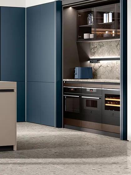 We specialize in creating clean, uncluttered spaces. Here, full-height panel doors in a striking blue matte finish conceal a complete appliance garage, including an oven, microwave, and wine cooler.