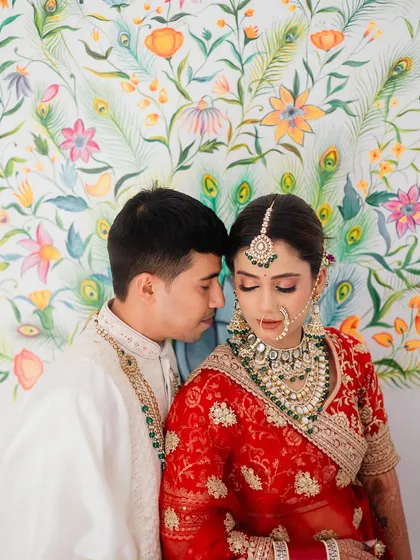 An intimate close-up of the couple against a vibrant, hand-painted backdrop in Udaipur. A beautiful blend of tradition and artistry.