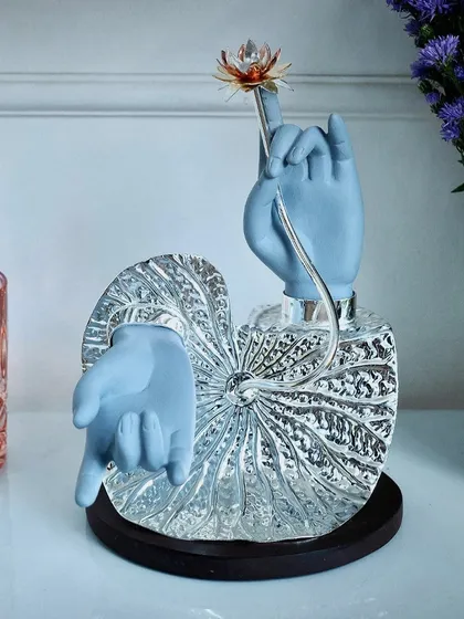 A divine blessing for new beginnings. This sculpture features Lord Krishna's hands on a silver leaf, offering a lotus flower. It is a heartfelt and artistic gift for baby showers and birth announcements.