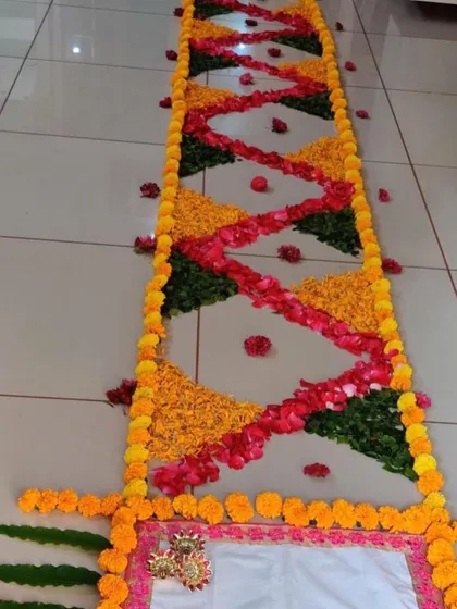 This is a floral runner or 'rangoli border' I made for a house entrance. The pattern is created with a mix of marigold petals, rose petals, and green leaves for a colorful and welcoming look.