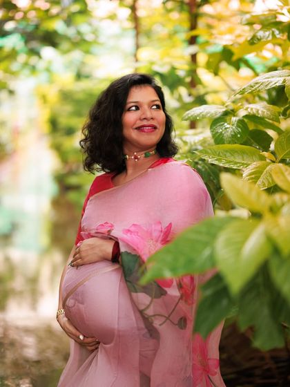 Surrounded by nature, this mama-to-be looks like a painting. The floral pink saree complements the lush greenery, creating a portrait of grace, strength, and new beginnings.