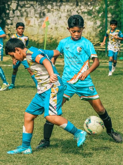 Two players in light blue jerseys work together to win the ball from an opponent.