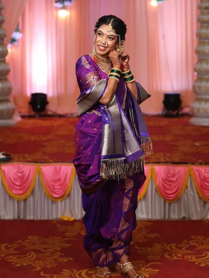 A full-length shot of a bride in a rich purple Nauvari saree. The draping is done to perfection, allowing for graceful movement.
