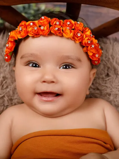 A beautiful, happy smile from an alert newborn with a sparkling orange floral headband. These moments are what make my job so rewarding.