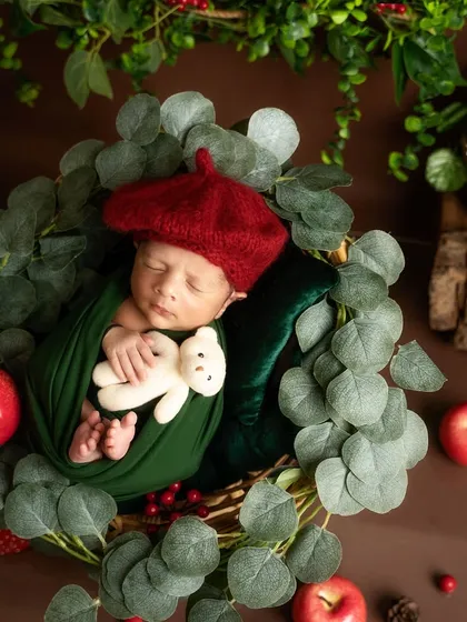 Cuddling a tiny teddy bear, this baby in a red beret is the picture of innocence. The apple and foliage props complete this creative, woodland artist theme.