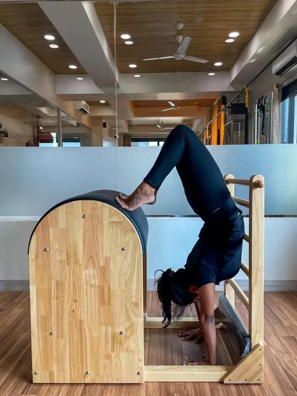 A client holding a handstand variation on the Ladder Barrel, an advanced move that builds shoulder stability and core power.