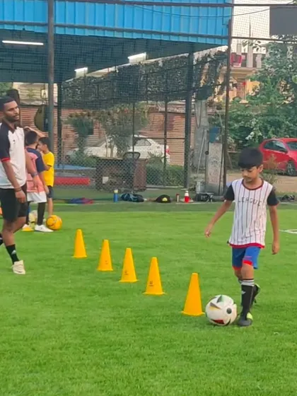 It all starts here, with one-on-one coaching and mastering the fundamentals. A coach guides a young player through a cone drill, focusing on ball control and agility.