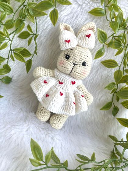 This sweet bunny is dressed in a white frock adorned with little red hearts. The matching bow on her ear makes her extra cute. A perfect gift for Valentine's Day or for someone you love.