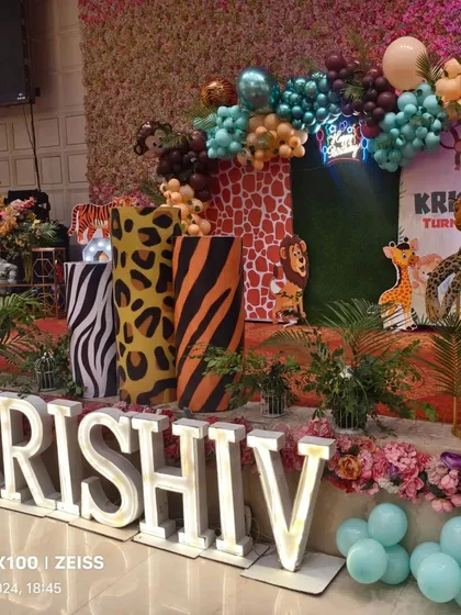 A close-up of the jungle stage, showing the detailed animal print plinths, marquee letters, and the mix of balloons and artificial plants.