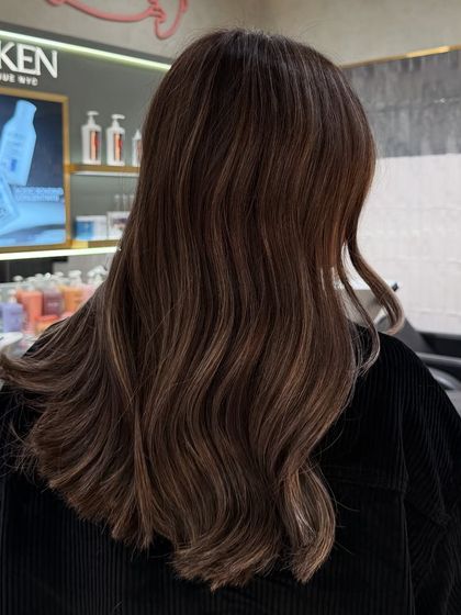 Another angle of a signature balayage, showing the beautiful blend of tones against the salon's Redken gloss bar.