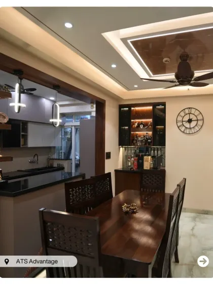A classic dining room with a dark wood table and intricately carved chairs. A built-in bar unit and a view into the kitchen make this a great space for entertaining.