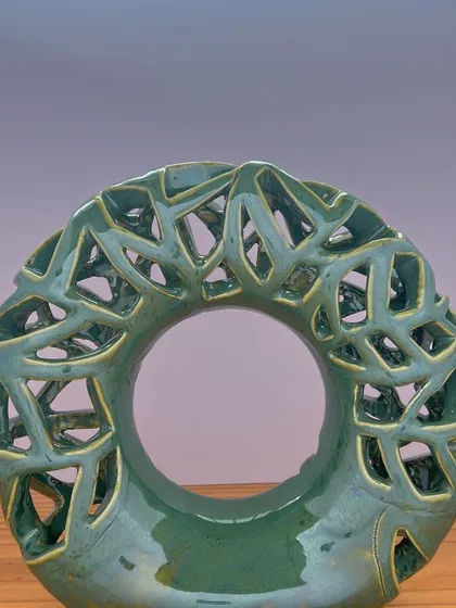 This is my Emerald Falls donut vase, a modern, sculptural piece with intricate, hand-carved details. It’s a statement piece that plays with light and shadow, designed to be beautiful with or without flowers.
