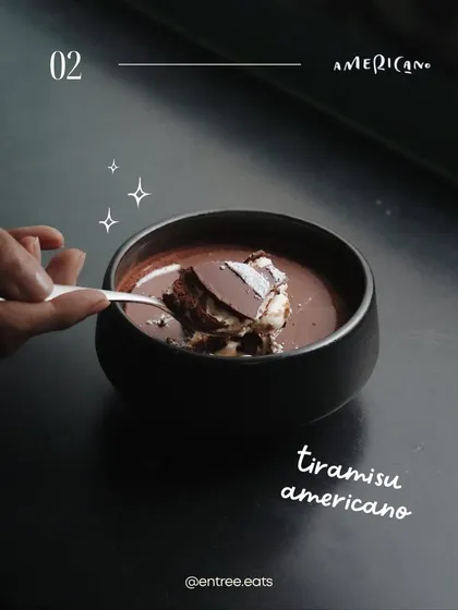 This Tiramisu Americano is shot with a dark, moody feel. The focus is on the rich, dark chocolate and the action of the spoon dipping in, creating a sense of indulgence and a sophisticated dessert experience.