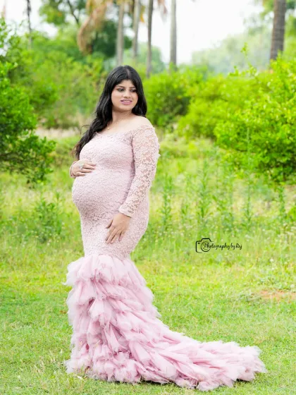 A solo portrait in a pink lace gown against a lush green background. This image showcases the elegance and serenity of pregnancy.