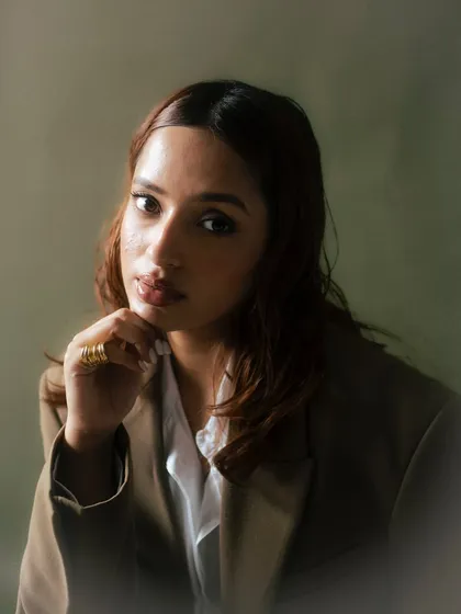 A soft, elegant portrait with a diffused, hazy effect. The olive green background and the model's gentle expression create a timeless and painterly quality, perfect for a sophisticated campaign.