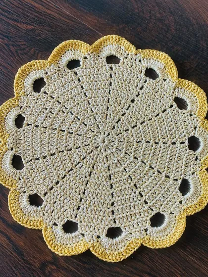 A clean, top-down shot of the beige doily with the openwork border.