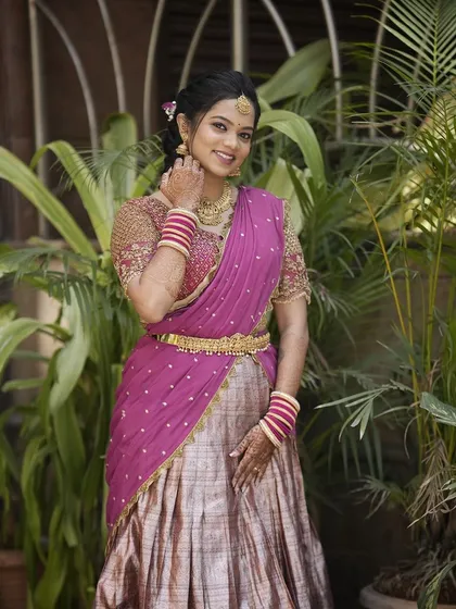 The bride posing in her beautiful pink and gold half-saree.