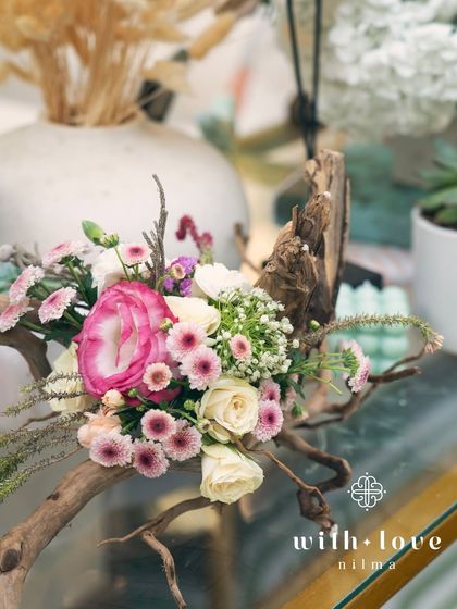 A small, artistic floral arrangement featuring driftwood, adding a rustic and natural touch to the baby shower decor.