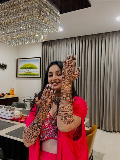 A happy client showing off her full-arm engagement mehendi. It's always a joy to see the final look come together with their festive attire.