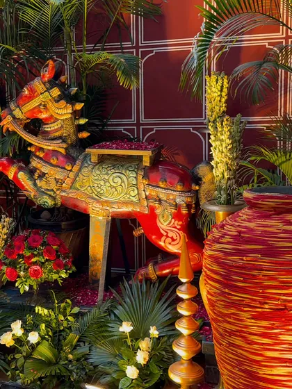 We specialize in creating immersive themes. This traditional Rajasthani event decor features an ornate, hand-painted horse prop surrounded by lush greenery and red roses, adding an authentic touch of royalty.