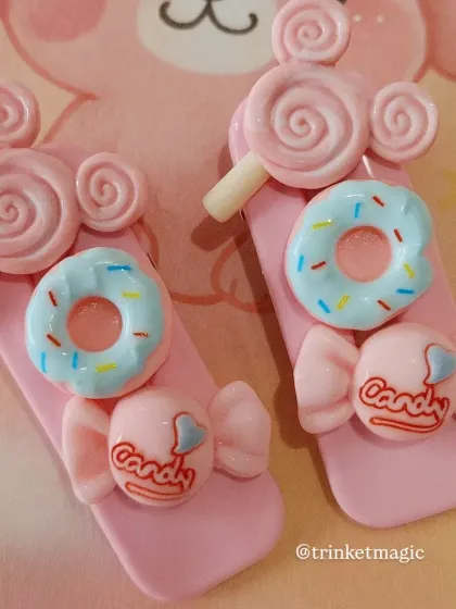 Sweet treats for your hair! This pair of pink hair clips is adorned with donut, candy, and lollipop charms. They are perfect for adding a playful and delicious touch to any look.