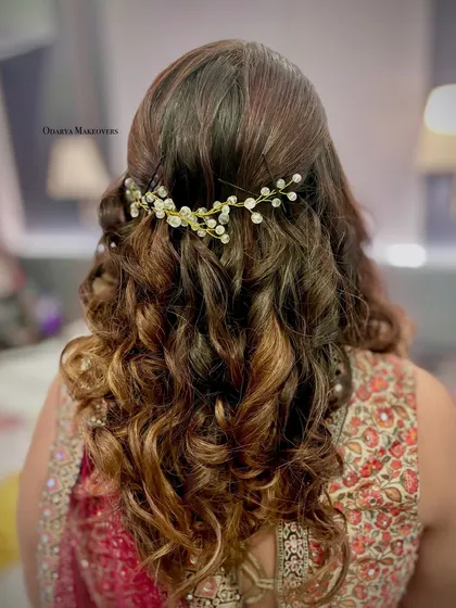 Soft, romantic curls are always a beautiful choice. This half-up hairstyle is decorated with a delicate pearl hair vine, perfect for an engagement or reception look.