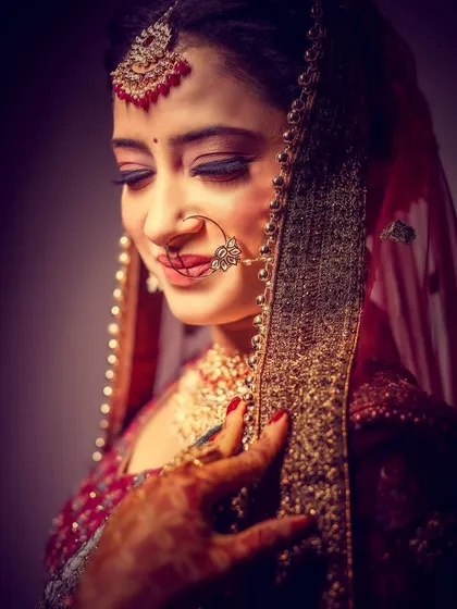 A classic and elegant bridal portrait. The soft lighting and the bride's gentle expression, framed by her veil, create a timeless and beautiful image.